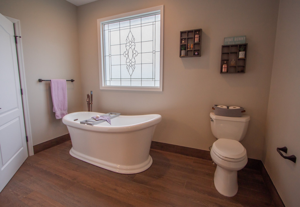 Inredning av ett klassiskt stort en-suite badrum, med ett fristående badkar, en toalettstol med separat cisternkåpa, klinkergolv i porslin och grått golv