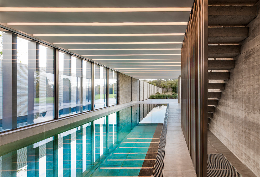 Photo of a contemporary indoor rectangular pool in London with concrete slab.