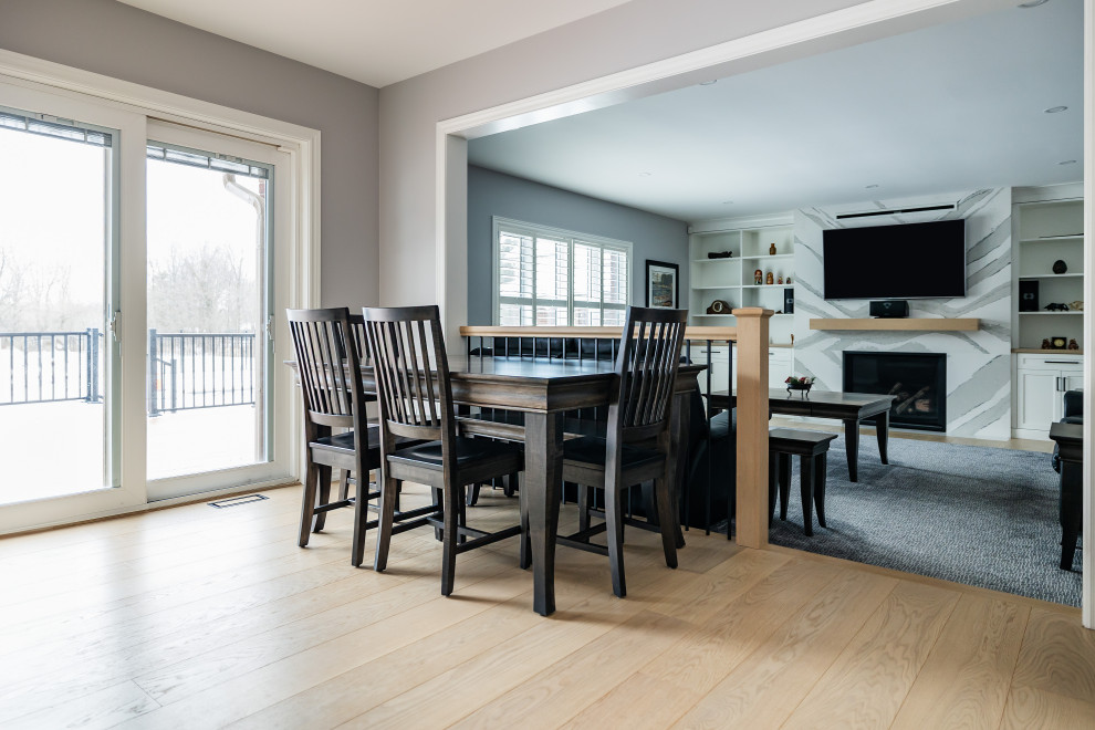 Mid-sized transitional u-shaped light wood floor eat-in kitchen photo in Toronto with an undermount sink, shaker cabinets, white cabinets, quartz countertops, white backsplash, quartz backsplash, stainless steel appliances, an island and white countertops