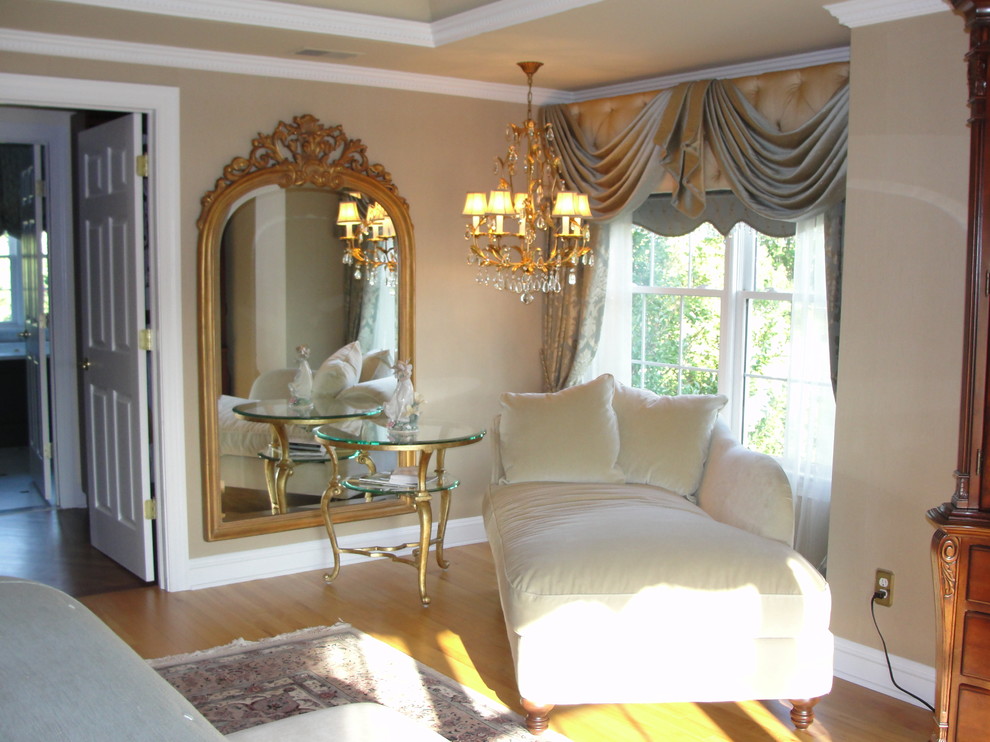 This is an example of a traditional master bedroom in New York with beige walls and light hardwood floors.