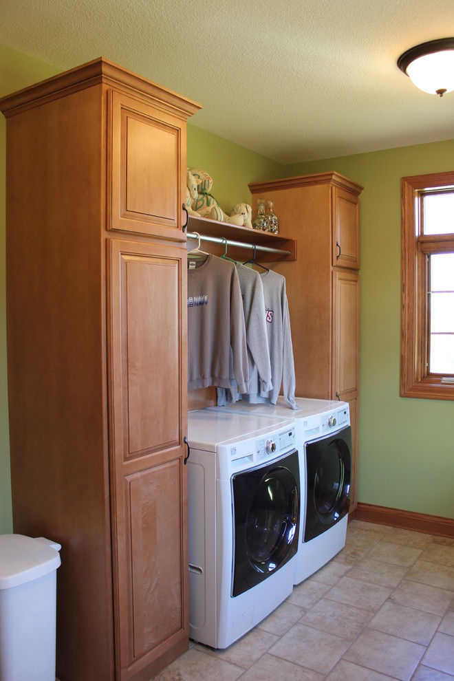 Dedicated laundry room - large transitional galley porcelain tile dedicated laundry room idea in Chicago with raised-panel cabinets, medium tone wood cabinets, a side-by-side washer/dryer and green walls