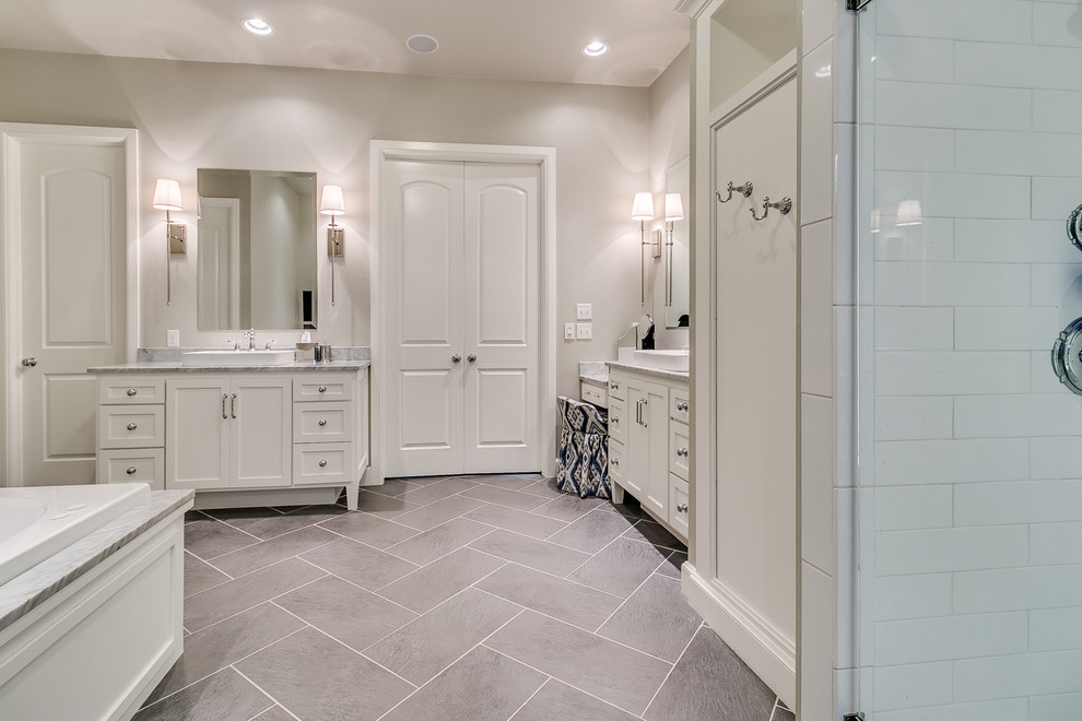Inspiration for a mid-sized transitional master bathroom in Oklahoma City with flat-panel cabinets, white cabinets, a drop-in tub, a curbless shower, a two-piece toilet, white tile, subway tile, beige walls, porcelain floors, a vessel sink, marble benchtops, grey floor and a hinged shower door.