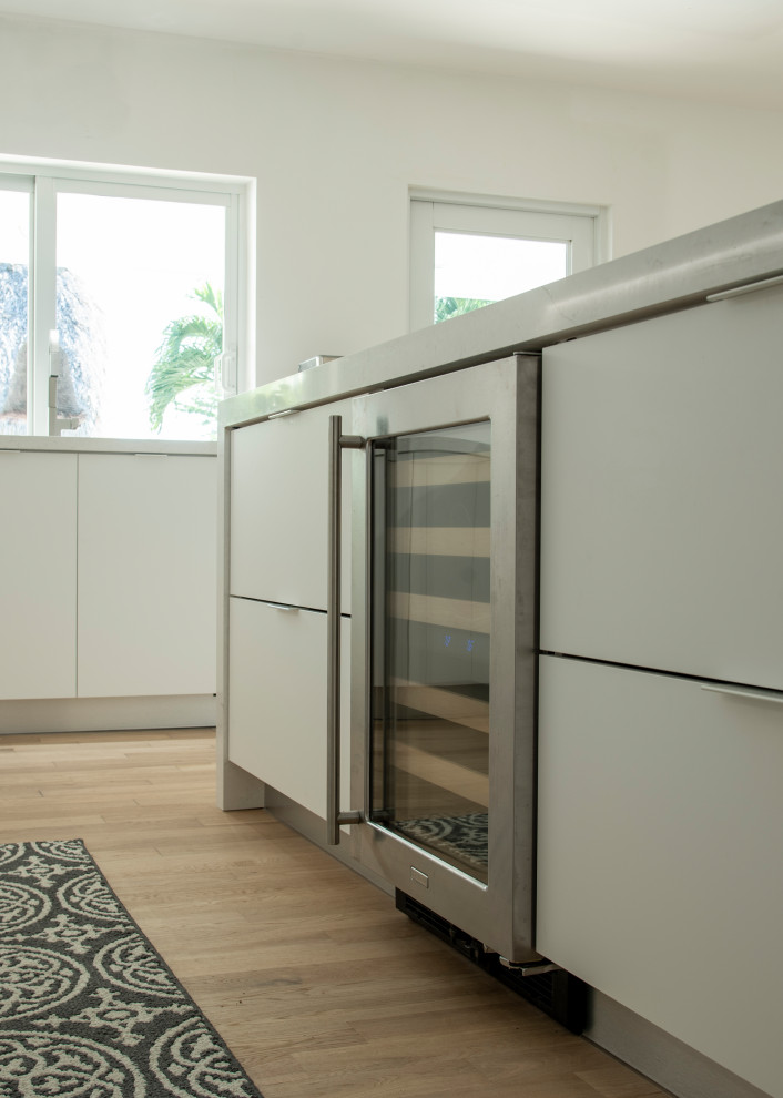 Open concept kitchen - large modern l-shaped medium tone wood floor and brown floor open concept kitchen idea in Miami with an undermount sink, flat-panel cabinets, white cabinets, quartz countertops, white backsplash, quartz backsplash, paneled appliances, an island and white countertops