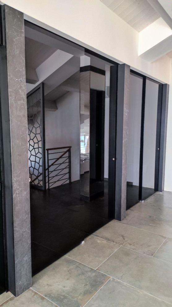 На фото: встроенный шкаф в стиле модернизм с стеклянными фасадами, черными фасадами, полом из керамогранита, серым полом и деревянным потолком с