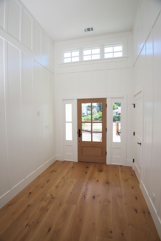 Inspiration for a mid-sized country foyer in San Francisco with white walls, light hardwood floors, a single front door, a medium wood front door and brown floor.