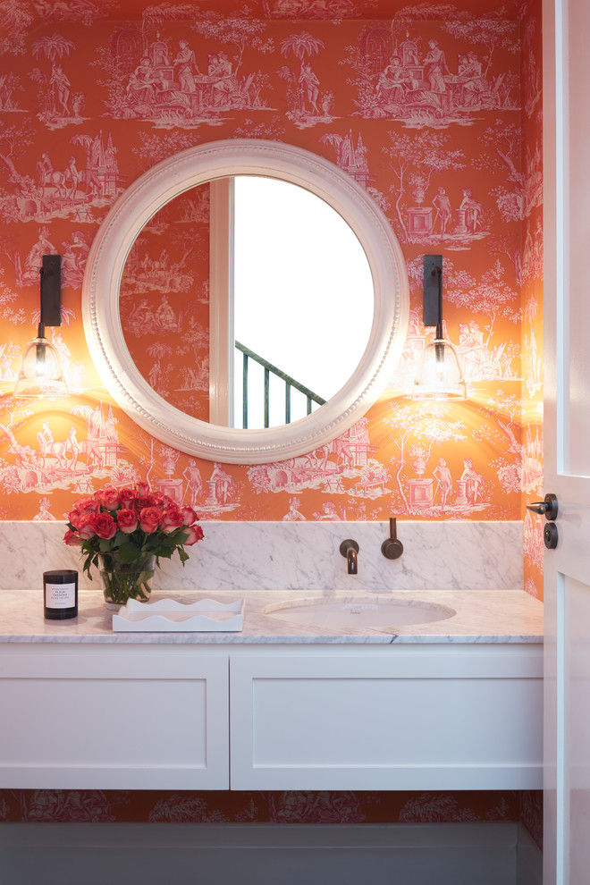 Photo of a transitional powder room in Other with shaker cabinets, white cabinets, orange walls and white benchtops.