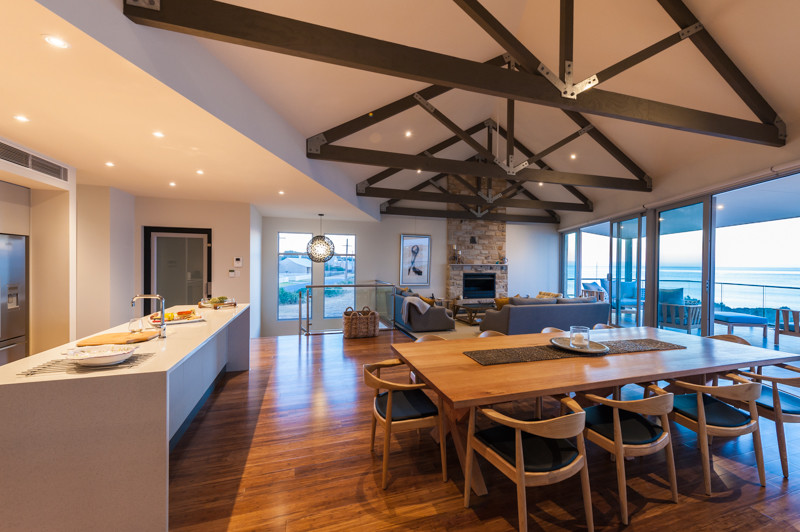Photo of a large beach style open plan dining in Adelaide with white walls, bamboo floors, a stone fireplace surround and a standard fireplace.