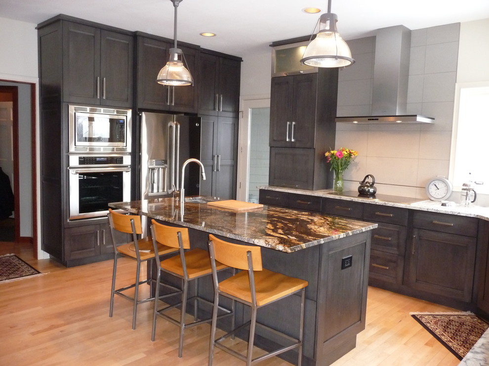 Example of a large transitional u-shaped light wood floor eat-in kitchen design in Milwaukee with an undermount sink, flat-panel cabinets, gray cabinets, granite countertops, white backsplash, porcelain backsplash, stainless steel appliances and an island