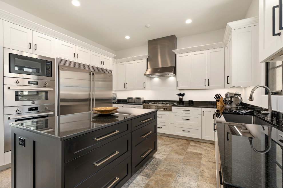 Example of a huge u-shaped enclosed kitchen design with white cabinets, white backsplash, stainless steel appliances, an island and black countertops