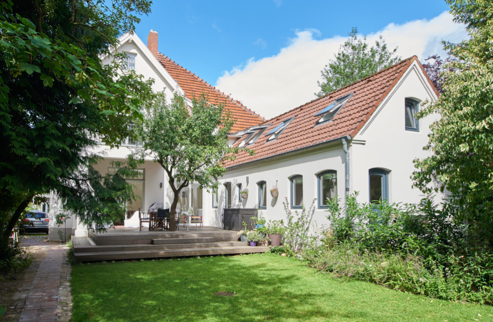 Example of a large classic white two-story stucco exterior home design in Hamburg with a tile roof and a red roof
