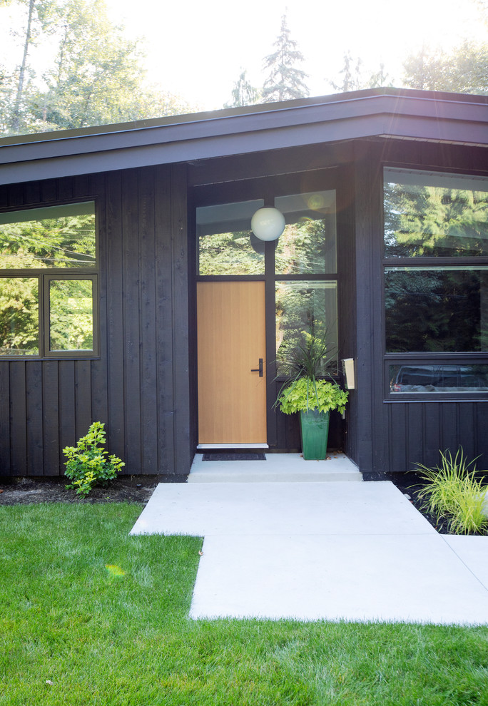Photo of a mid-sized midcentury one-storey black house exterior in Vancouver with a gable roof.