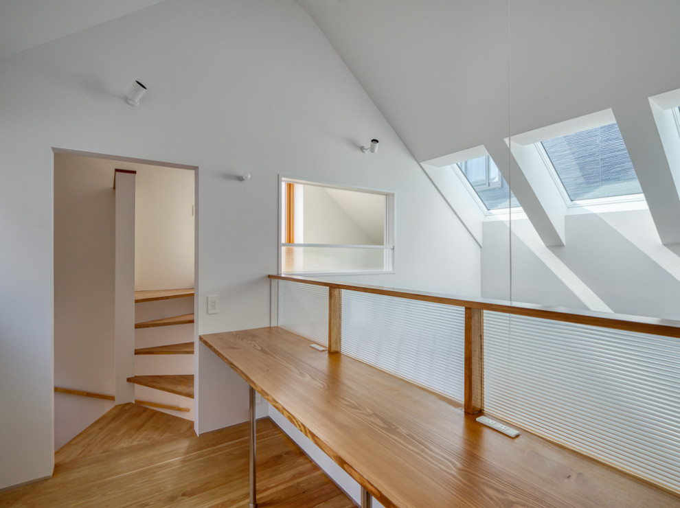 Inspiration för små moderna hemmabibliotek, med vita väggar, målat trägolv, ett inbyggt skrivbord och brunt golv