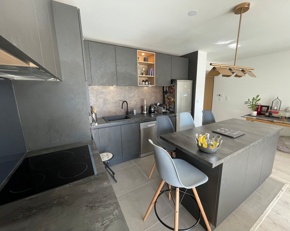 Mid-sized modern l-shaped open plan kitchen in Toulouse with an undermount sink, beaded inset cabinets, stainless steel cabinets, quartzite benchtops, grey splashback, glass tile splashback, panelled appliances, porcelain floors, with island, grey floor and grey benchtop.