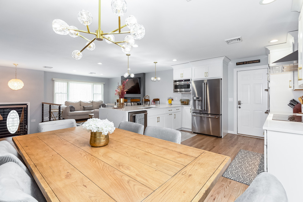 Exempel på ett mellanstort klassiskt vit vitt kök, med en undermonterad diskho, skåp i shakerstil, vita skåp, bänkskiva i kvarts, grått stänkskydd, stänkskydd i marmor, rostfria vitvaror, ljust trägolv, en halv köksö och brunt golv