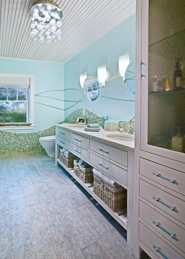 Photo of a contemporary kids bathroom in Boston with an undermount sink, flat-panel cabinets, white cabinets, limestone benchtops, a corner tub, a shower/bathtub combo, a two-piece toilet, multi-coloured tile, blue walls and porcelain floors.