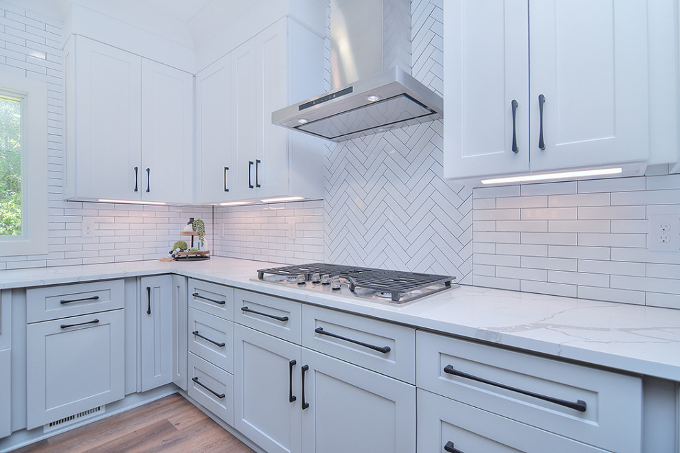 Example of a transitional brown floor kitchen design in Charlotte with flat-panel cabinets, white cabinets, quartz countertops, white backsplash, ceramic backsplash, stainless steel appliances, an island and white countertops