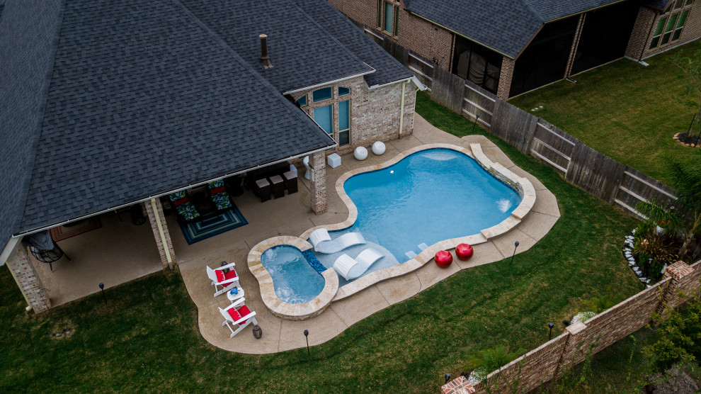 Photo of a mid-sized tropical backyard custom-shaped pool in Houston.