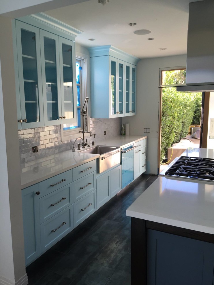 Inspiration for a mid-sized transitional galley open plan kitchen in Los Angeles with a farmhouse sink, shaker cabinets, blue cabinets, quartz benchtops, grey splashback, subway tile splashback, stainless steel appliances, dark hardwood floors, with island and brown floor.
