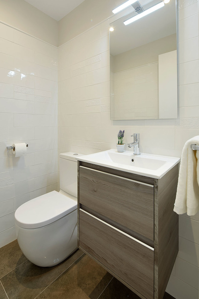 Modelo de aseo minimalista pequeño con armarios con paneles con relieve, puertas de armario de madera oscura, sanitario de una pieza, baldosas y/o azulejos blancos, baldosas y/o azulejos de cerámica, paredes blancas, suelo de baldosas de porcelana, lavabo integrado y encimera de acrílico