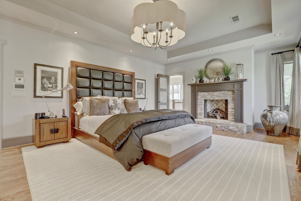 Design ideas for a large transitional master bedroom in Atlanta with white walls, medium hardwood floors, brown floor, a standard fireplace and a stone fireplace surround.
