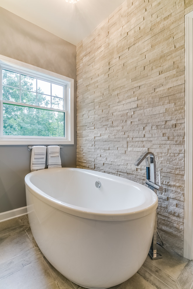 Photo of a mid-sized transitional master bathroom in Milwaukee with shaker cabinets, white cabinets, a freestanding tub, beige tile, stone tile, grey walls, ceramic floors, an undermount sink and granite benchtops.