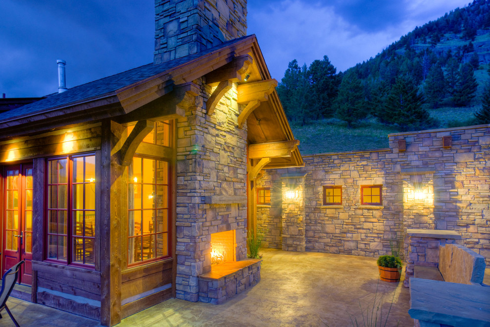 Example of a large mountain style backyard concrete patio design with a fire pit and no cover