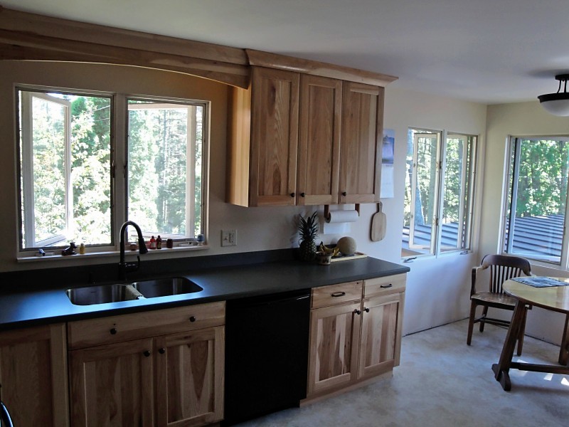 Inspiration for a mid-sized rustic l-shaped linoleum floor and gray floor eat-in kitchen remodel with an integrated sink, flat-panel cabinets, light wood cabinets, laminate countertops, black appliances and gray countertops