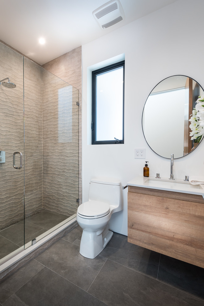 This is an example of a mid-sized contemporary master bathroom in Los Angeles with flat-panel cabinets, light wood cabinets, a double shower, a one-piece toilet, brown tile, stone tile, white walls, slate floors, an undermount sink, engineered quartz benchtops, grey floor, a hinged shower door and white benchtops.