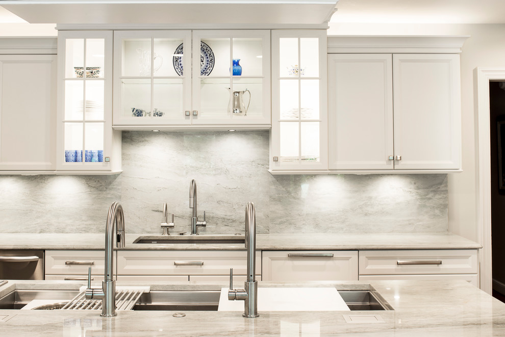 Example of a large transitional single-wall medium tone wood floor and brown floor kitchen design in Denver with an undermount sink, recessed-panel cabinets, white cabinets, white backsplash, stone slab backsplash, stainless steel appliances and an island