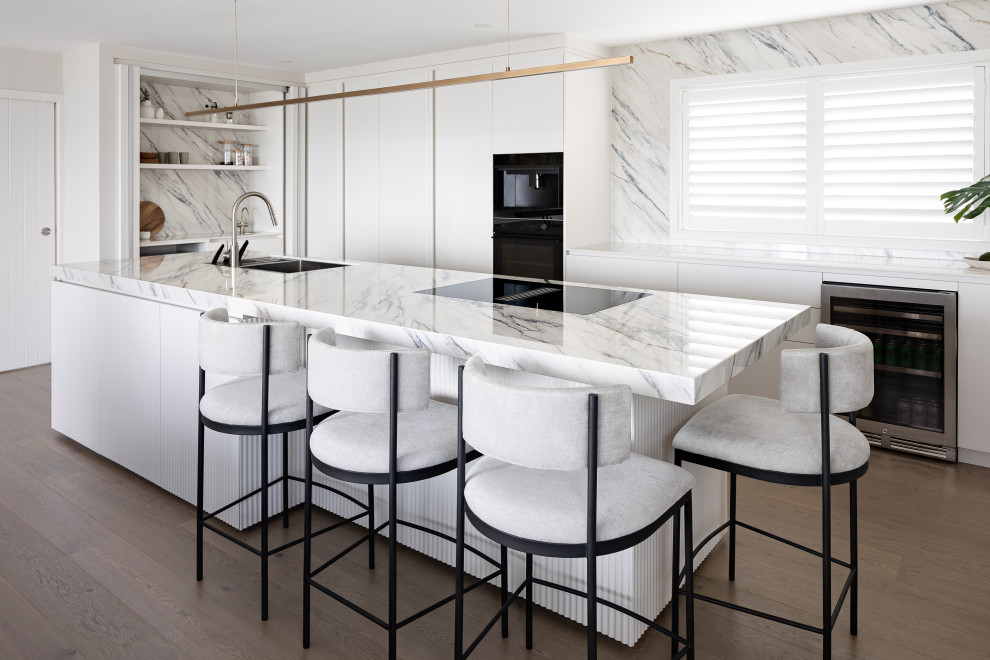 Idéer för ett stort modernt vit l-kök, med vita skåp, en köksö, en undermonterad diskho, släta luckor, rostfria vitvaror, mörkt trägolv och brunt golv
