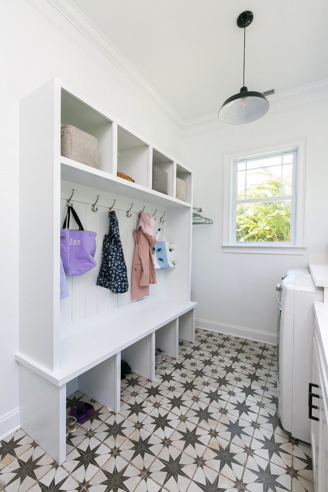This is an example of a large country utility room in Charleston with an undermount sink, white cabinets, quartz benchtops, white walls, concrete floors and a side-by-side washer and dryer.