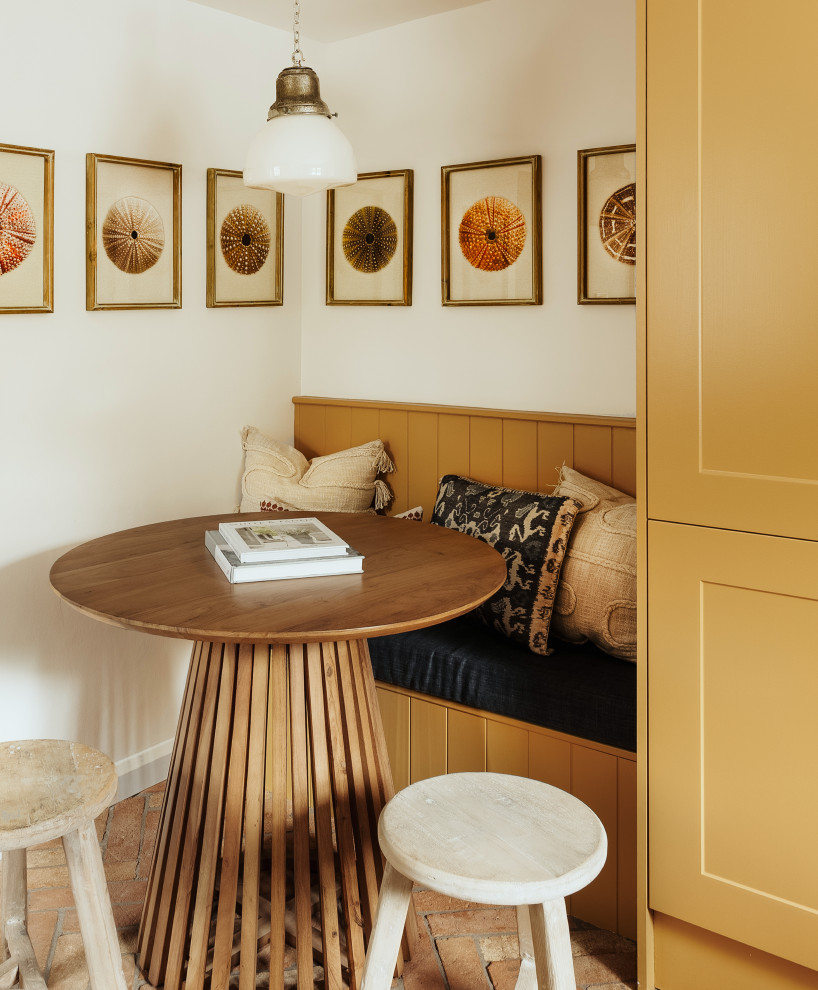 Small eclectic dining room in Cornwall with terra-cotta floors and brown floor.