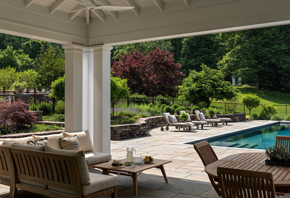 This is an example of a mid-sized transitional backyard rectangular pool in New York with natural stone pavers.