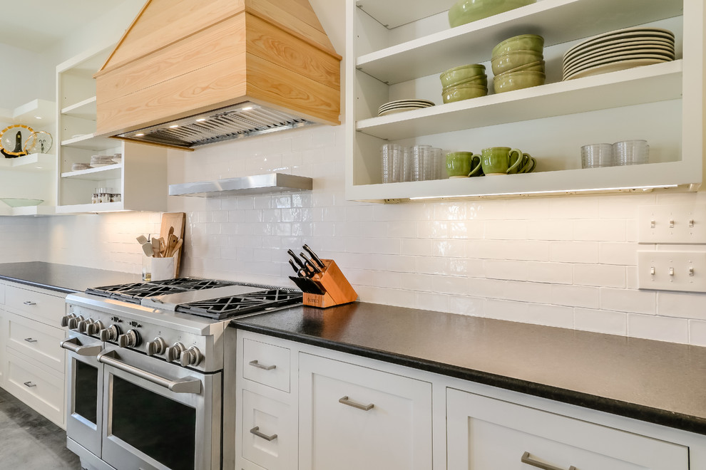 This is an example of a large country l-shaped eat-in kitchen in Jackson with a farmhouse sink, shaker cabinets, white cabinets, quartzite benchtops, white splashback, subway tile splashback, panelled appliances, concrete floors, with island and grey floor.