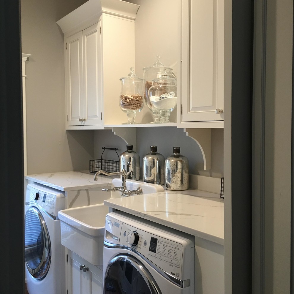 Inspiration for a traditional galley laundry cupboard in Detroit with a farmhouse sink, raised-panel cabinets, white cabinets, marble benchtops, grey walls, medium hardwood floors, a side-by-side washer and dryer and brown floor.