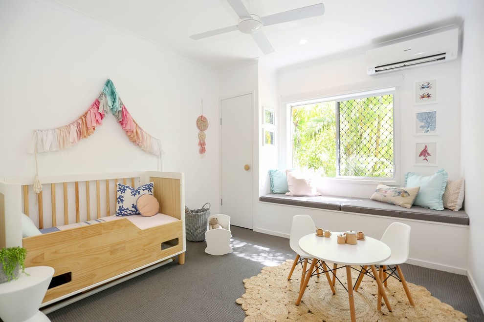 This is an example of a beach style kids' room for girls in Other with white walls, carpet and grey floor.