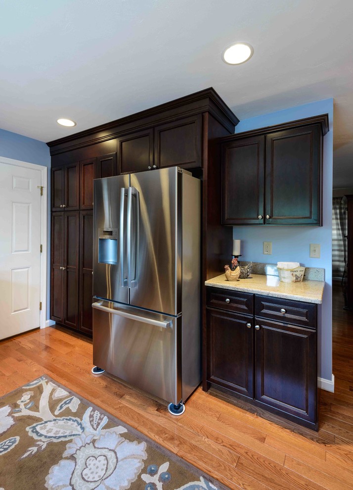Enclosed kitchen - mid-sized transitional u-shaped light wood floor enclosed kitchen idea with raised-panel cabinets, dark wood cabinets, quartz countertops, stainless steel appliances, an undermount sink and an island