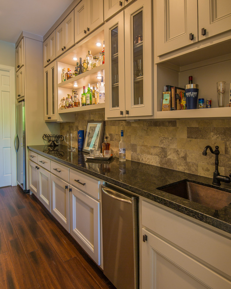 This is an example of a large traditional galley kitchen pantry in Houston with an undermount sink, recessed-panel cabinets, grey cabinets, granite benchtops, beige splashback, travertine splashback, stainless steel appliances, bamboo floors, no island, brown floor and brown benchtop.
