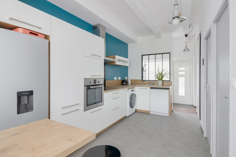Contemporary l-shaped kitchen in Nantes with flat-panel cabinets, white cabinets, blue splashback, concrete floors, grey floor and beige benchtop.