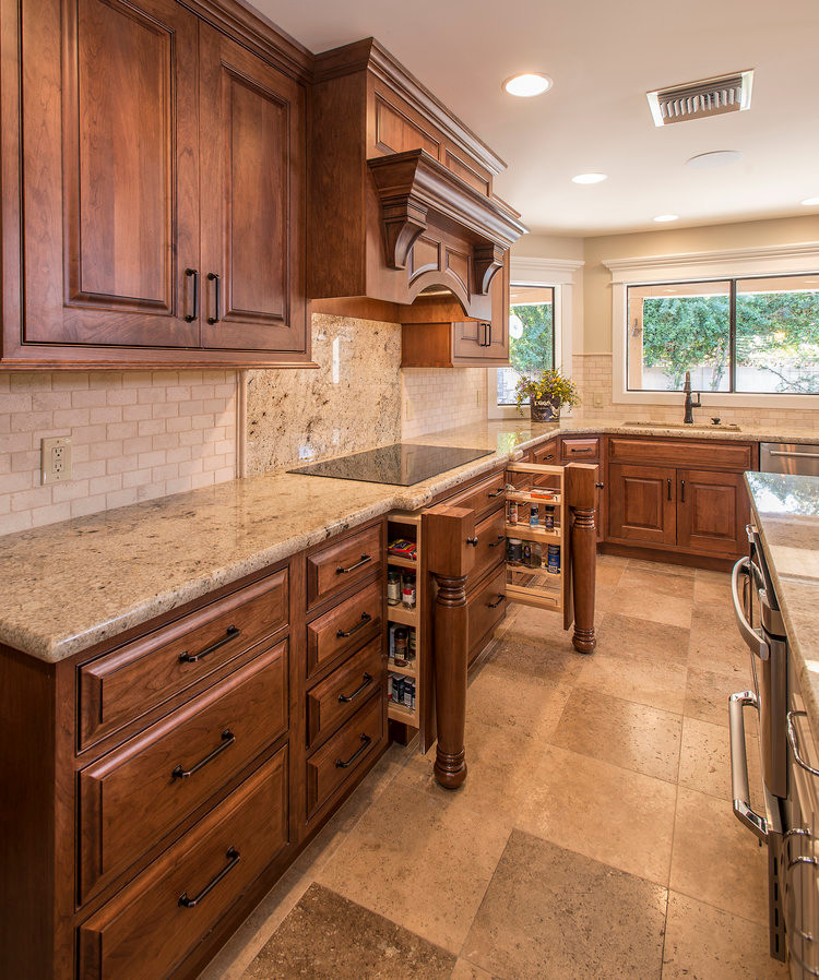 This is an example of a large arts and crafts l-shaped eat-in kitchen in San Diego with an undermount sink, raised-panel cabinets, medium wood cabinets, granite benchtops, stainless steel appliances, travertine floors, with island and beige floor.