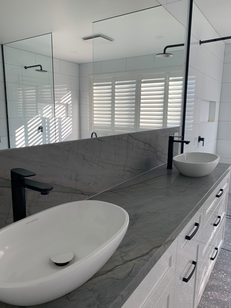 Large minimalist white tile and porcelain tile terrazzo floor, gray floor and double-sink bathroom photo in Melbourne with shaker cabinets, white cabinets, a one-piece toilet, white walls, a vessel sink, granite countertops, a freestanding vanity and gray countertops