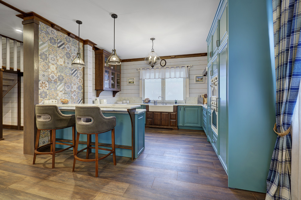 Country u-shaped kitchen in Moscow with a farmhouse sink, raised-panel cabinets, turquoise cabinets, dark hardwood floors, a peninsula, brown floor, white benchtop, white splashback and white appliances.