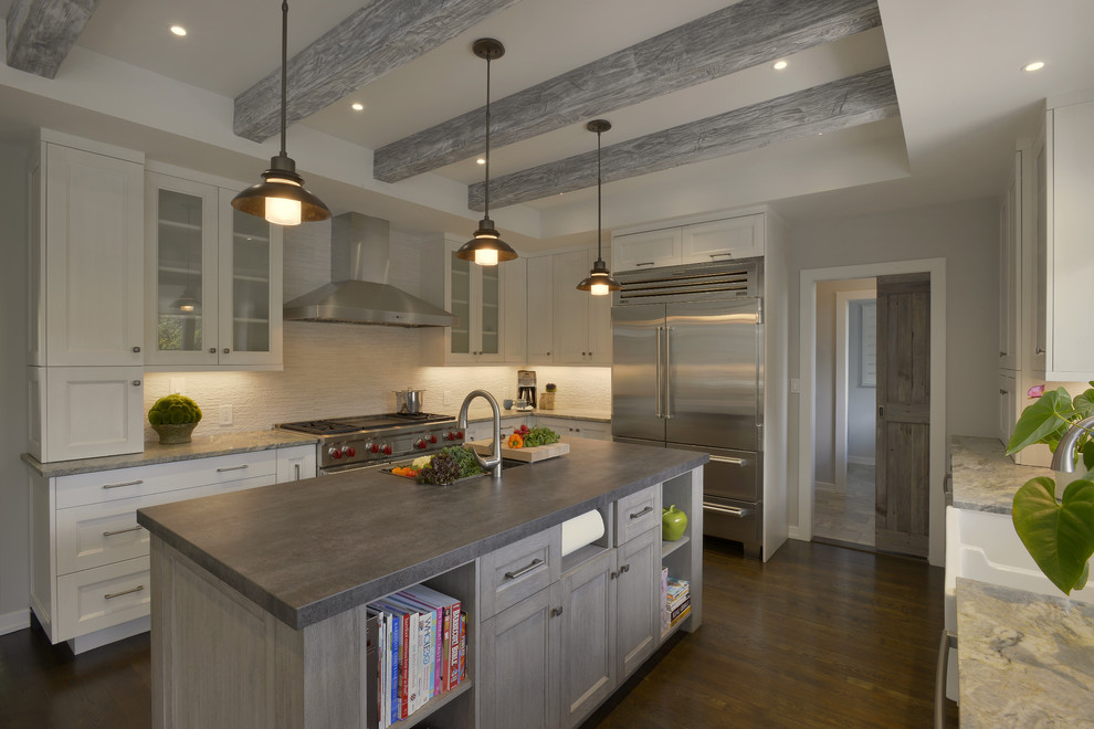 Photo of a large country u-shaped eat-in kitchen in New York with a farmhouse sink, glass-front cabinets, white cabinets, solid surface benchtops, white splashback, porcelain splashback, stainless steel appliances, medium hardwood floors, with island and brown floor.