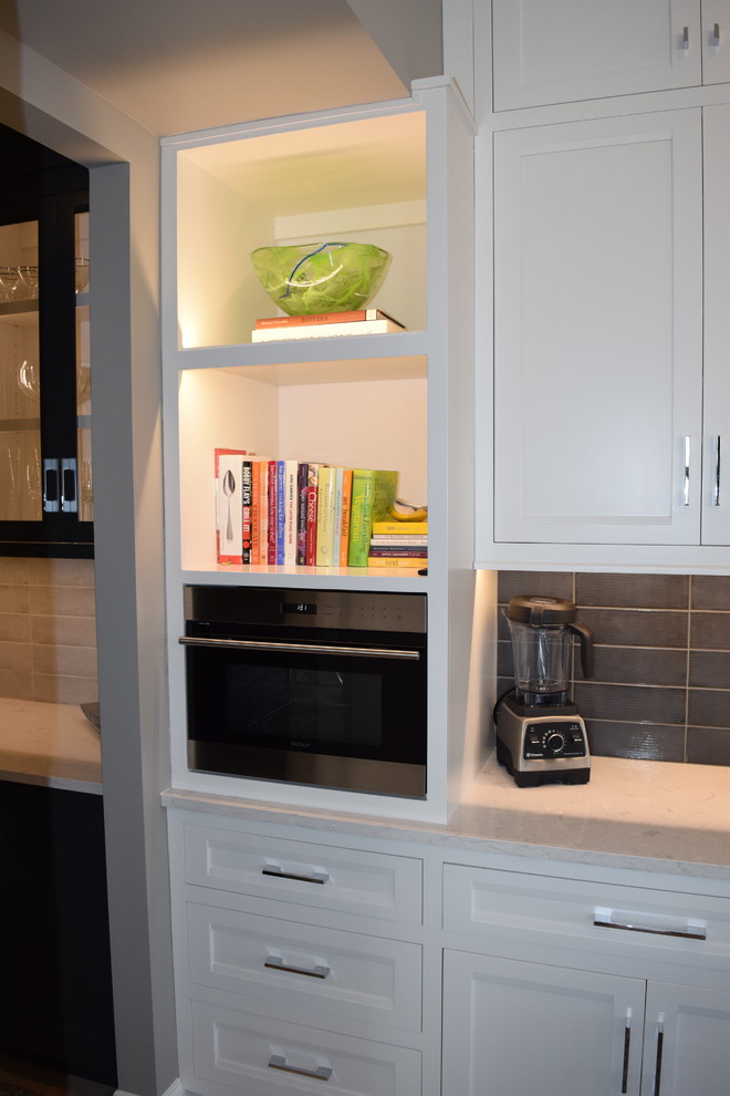 Inspiration for a large transitional l-shaped light wood floor and multicolored floor eat-in kitchen remodel in Chicago with beaded inset cabinets, white cabinets, quartz countertops, black backsplash, ceramic backsplash, stainless steel appliances and an island