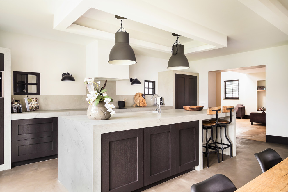 This is an example of a transitional galley kitchen in Grand Rapids with shaker cabinets, dark wood cabinets, grey splashback, concrete floors, with island, grey floor and grey benchtop.