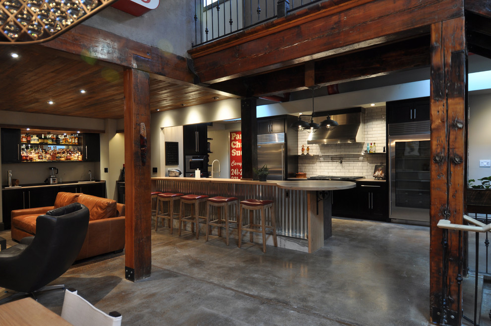 Large industrial u-shaped eat-in kitchen in St Louis with a farmhouse sink, shaker cabinets, dark wood cabinets, wood benchtops, white splashback, subway tile splashback, stainless steel appliances, concrete floors, a peninsula and grey floor.