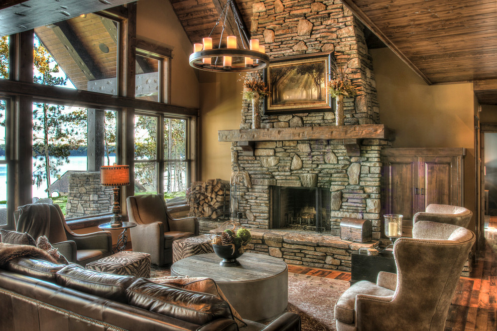 Inspiration for a large country open concept living room in Minneapolis with medium hardwood floors, a standard fireplace, a stone fireplace surround, no tv, brown floor and brown walls.