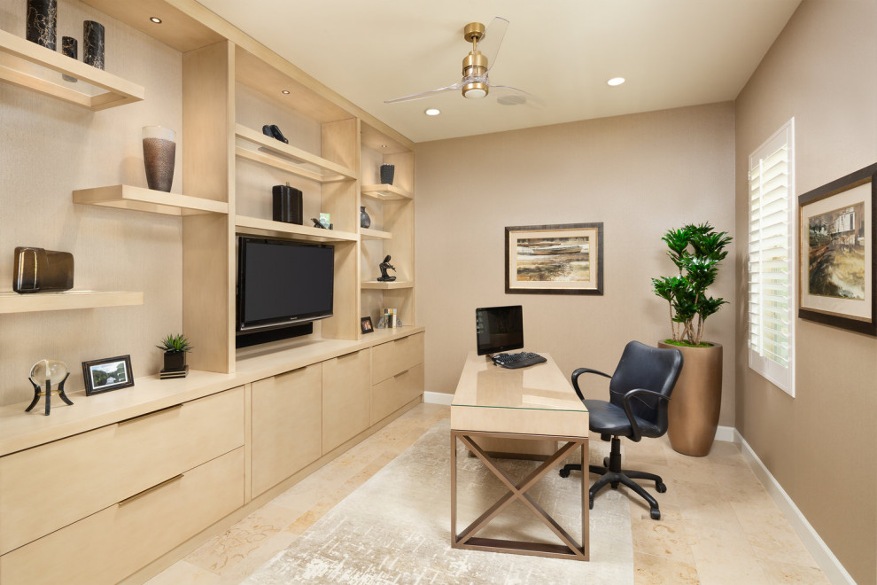 Design ideas for a small contemporary home office in Orange County with a library, beige walls, limestone floors, a freestanding desk and beige floor.