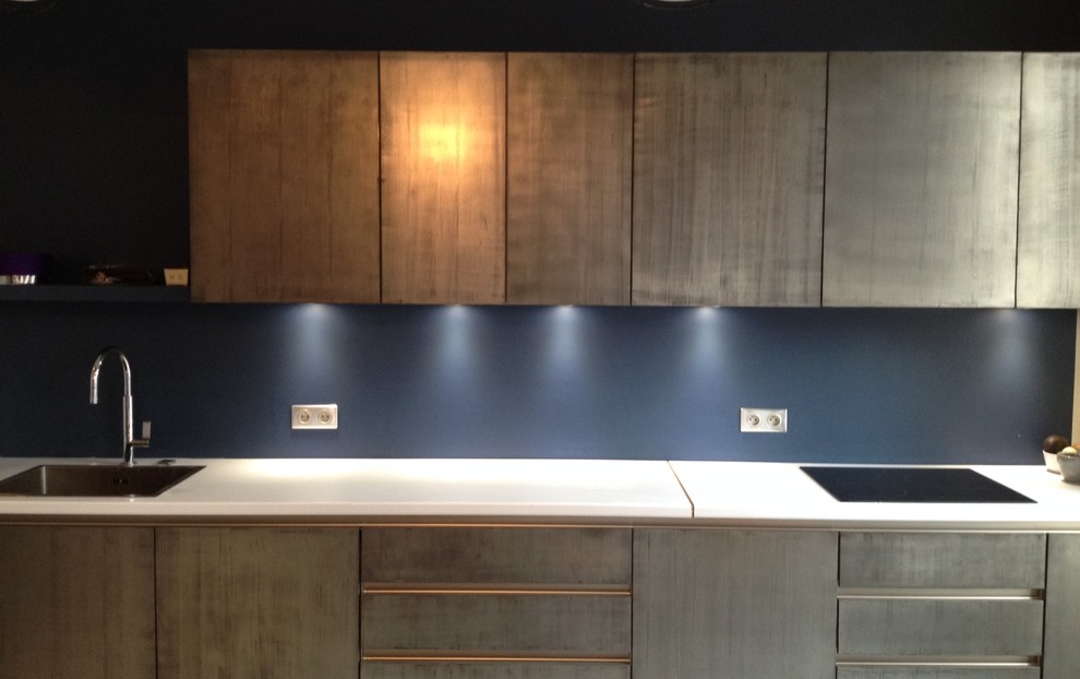 This is an example of a mid-sized contemporary single-wall separate kitchen in Paris with a single-bowl sink, beaded inset cabinets, stainless steel cabinets, solid surface benchtops, brown splashback, timber splashback, stainless steel appliances, linoleum floors, with island and grey floor.