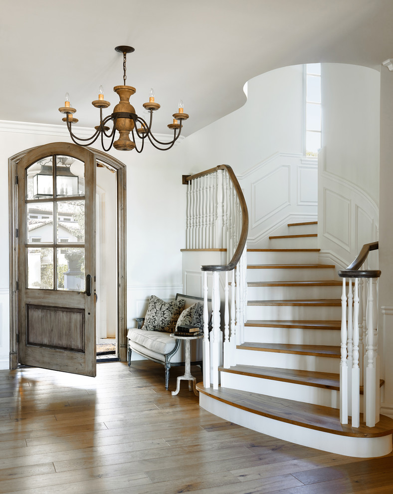This is an example of a mediterranean foyer in Phoenix with white walls, medium hardwood floors, a single front door and a medium wood front door.